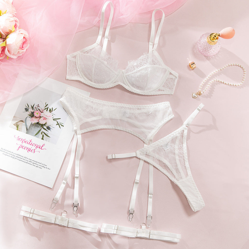 White lace four-piece lingerie set arranged flat.