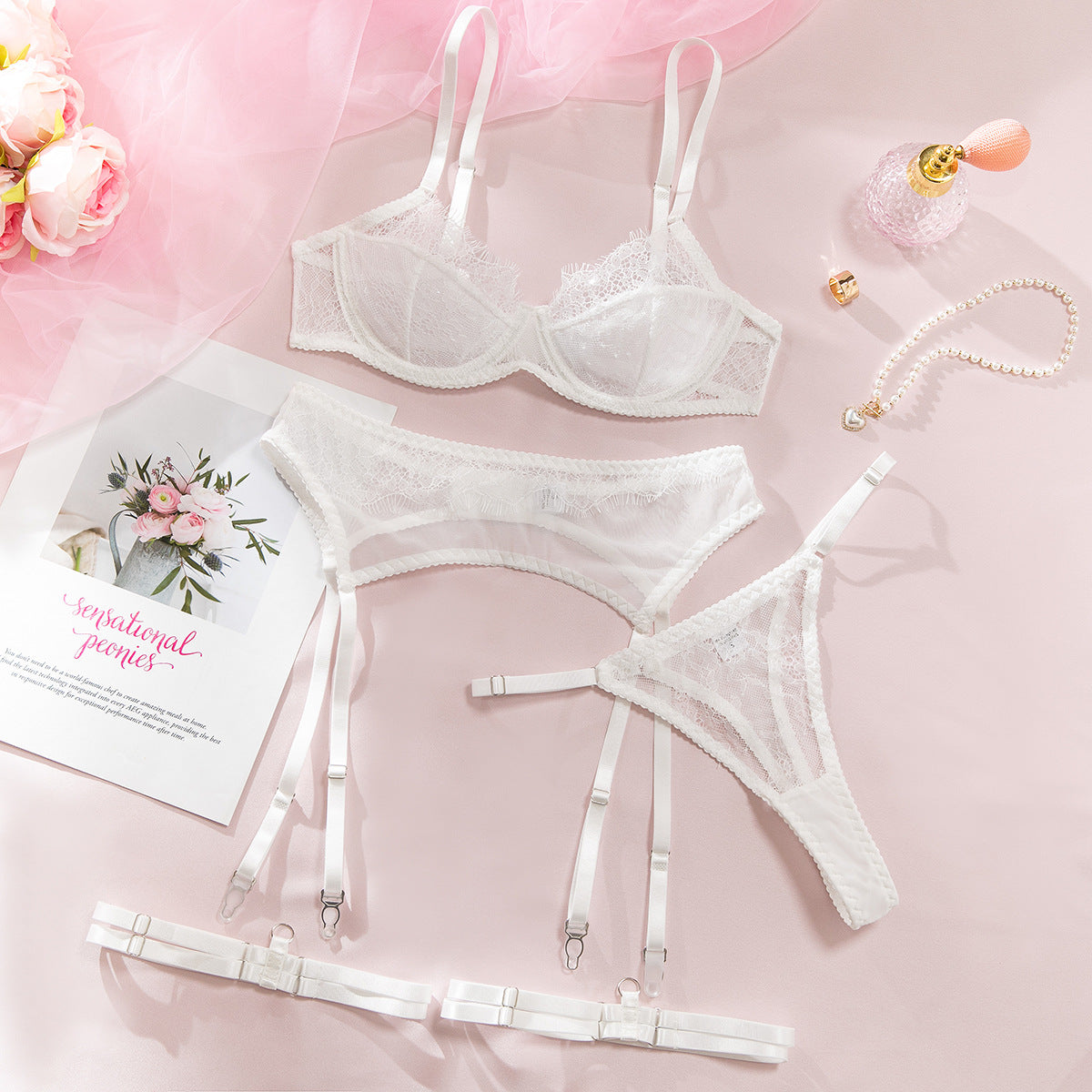 White lace four-piece lingerie set arranged flat.