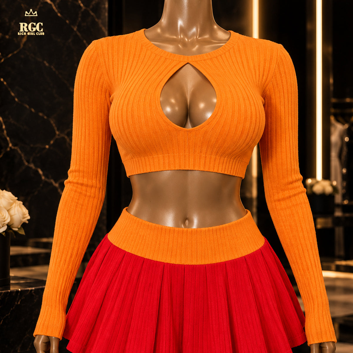 Pumpkin Patch Power Set close-up showing the orange ribbed keyhole top, broad orange waistband, and red pleated skirt