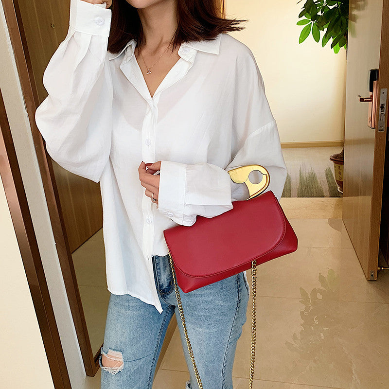 Model carrying the red Power Move Top-Handle Bag with gold-tone handle and chain strap