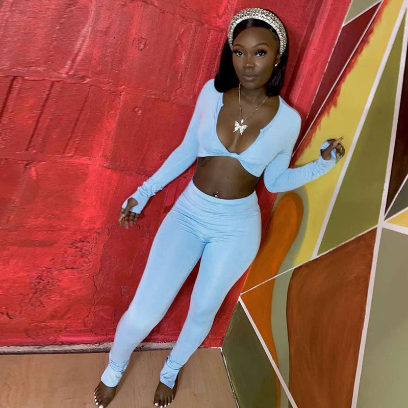 Adult model wearing the blue long-sleeve crop top and matching fitted jogger pants against a colorful wall.