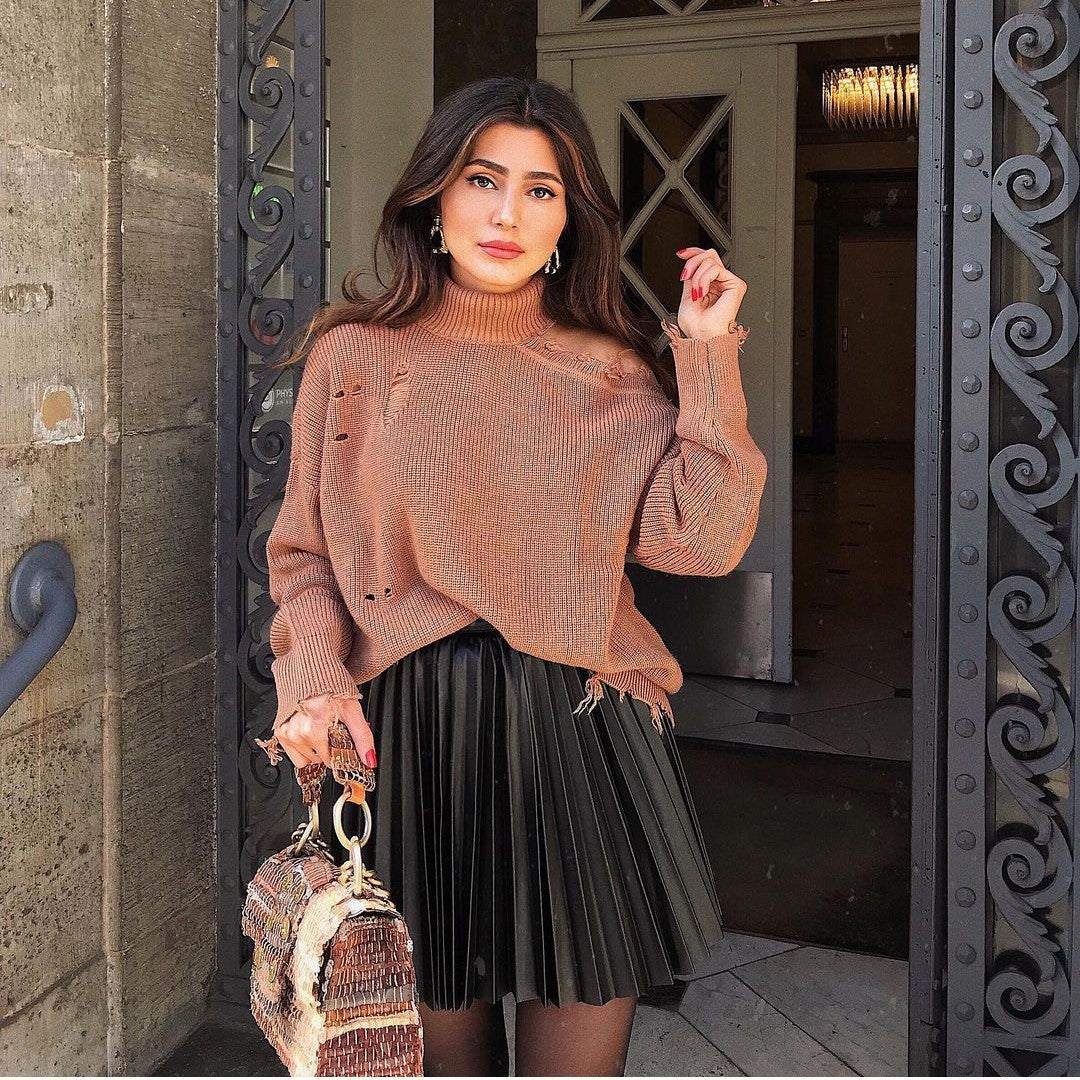 Adult model wearing the black accordion-pleat mini skirt with a distressed brown turtleneck; handbag is styling only.