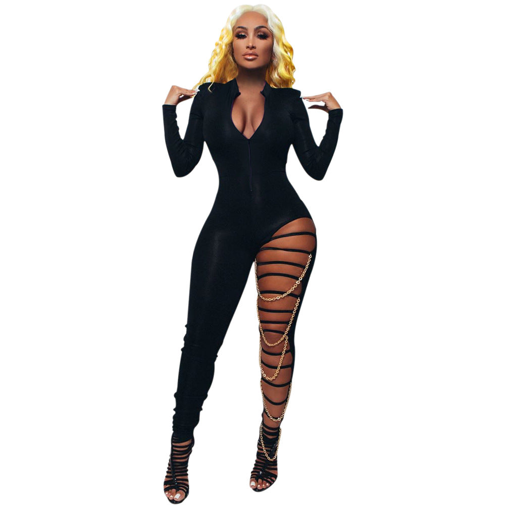 Adult model wearing the black Chain Reaction Deep-V Jumpsuit with zip front, asymmetric strapped leg cutout, and gold-tone chain drapes.