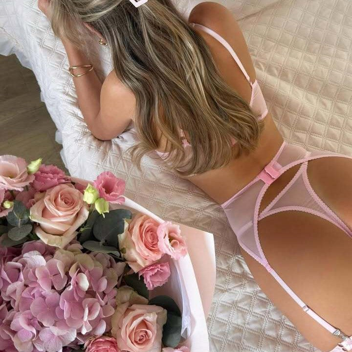 Adult model wearing the pink lace four-piece lingerie set, rear detail view.