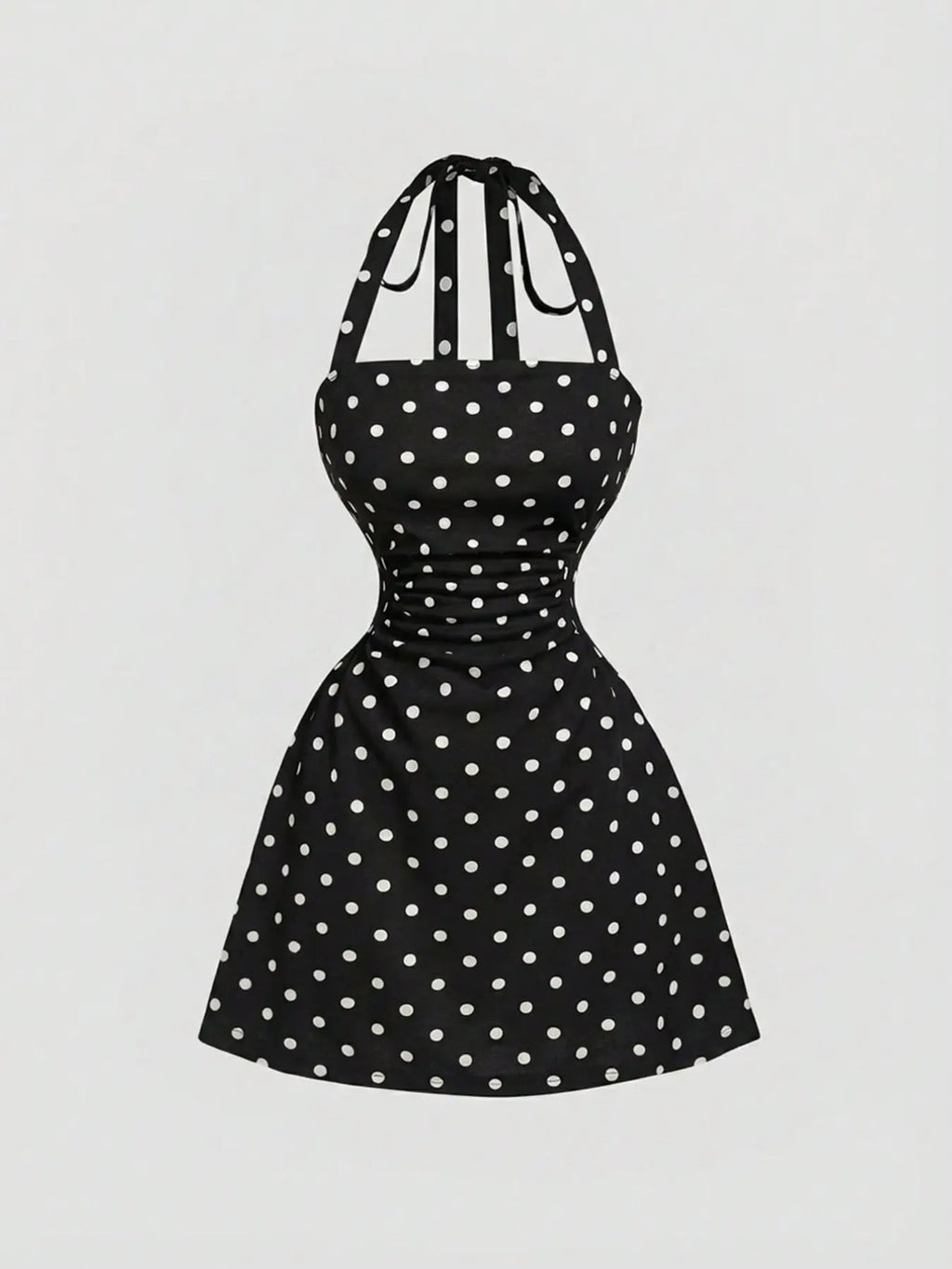 Black A-line mini dress with white polka dots, ruched waist and tie-back halter straps, front product view.