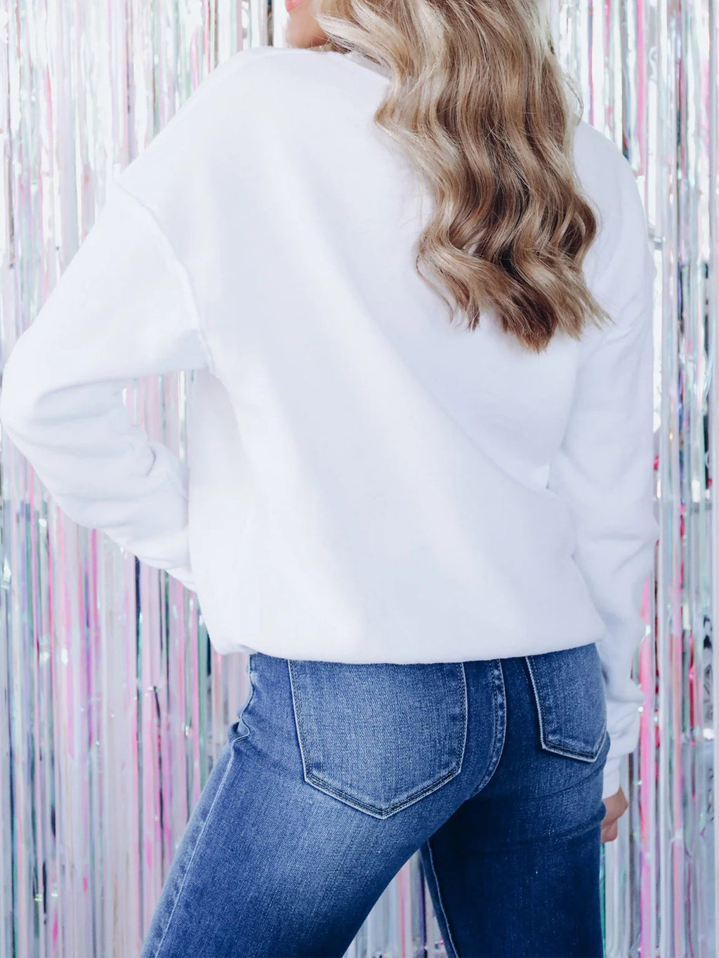 Adult model wearing the beige embroidered pullover with jeans, rear view showing the plain back.