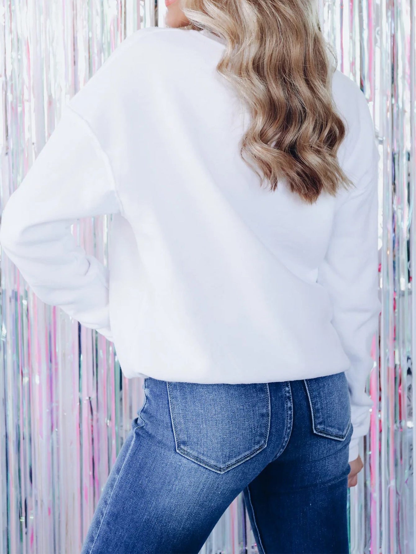 Adult model wearing the beige embroidered pullover with jeans, rear view showing the plain back.
