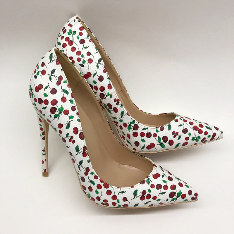 White cherry-print pointed-toe stiletto pumps shown as a pair