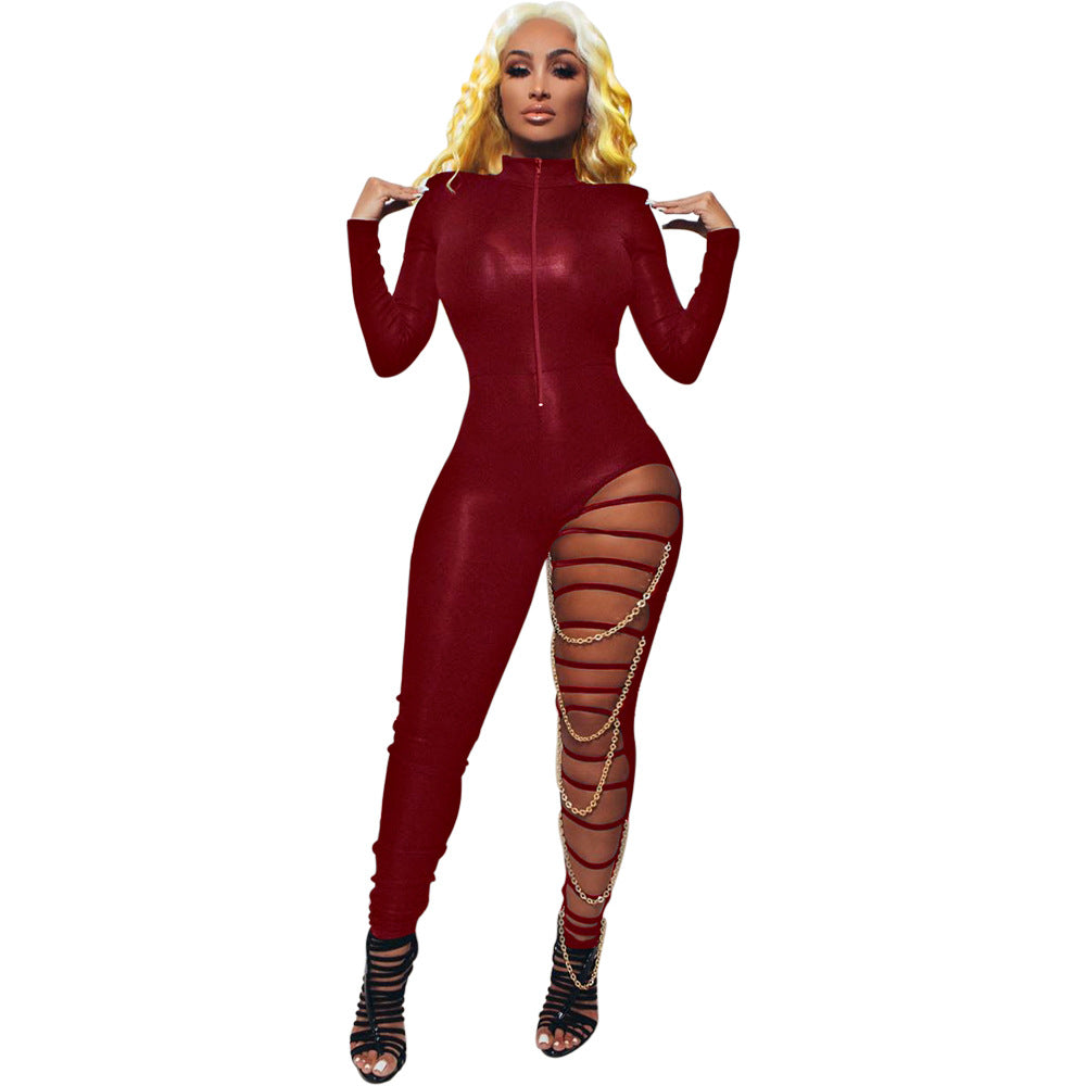 Adult model wearing the red zip-front Chain Reaction jumpsuit with high neckline, asymmetric strapped leg cutout, and gold-tone chain drapes.