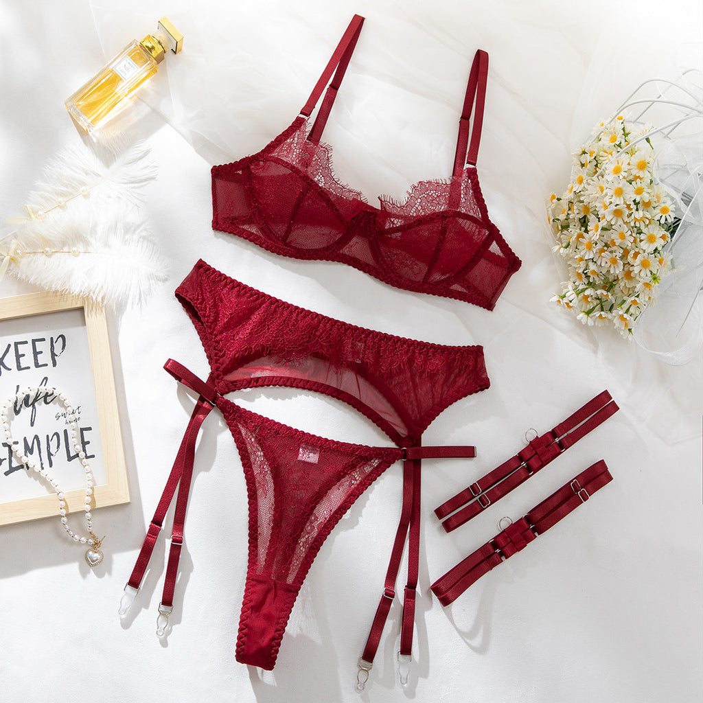 Wine-red lace four-piece lingerie set arranged flat.