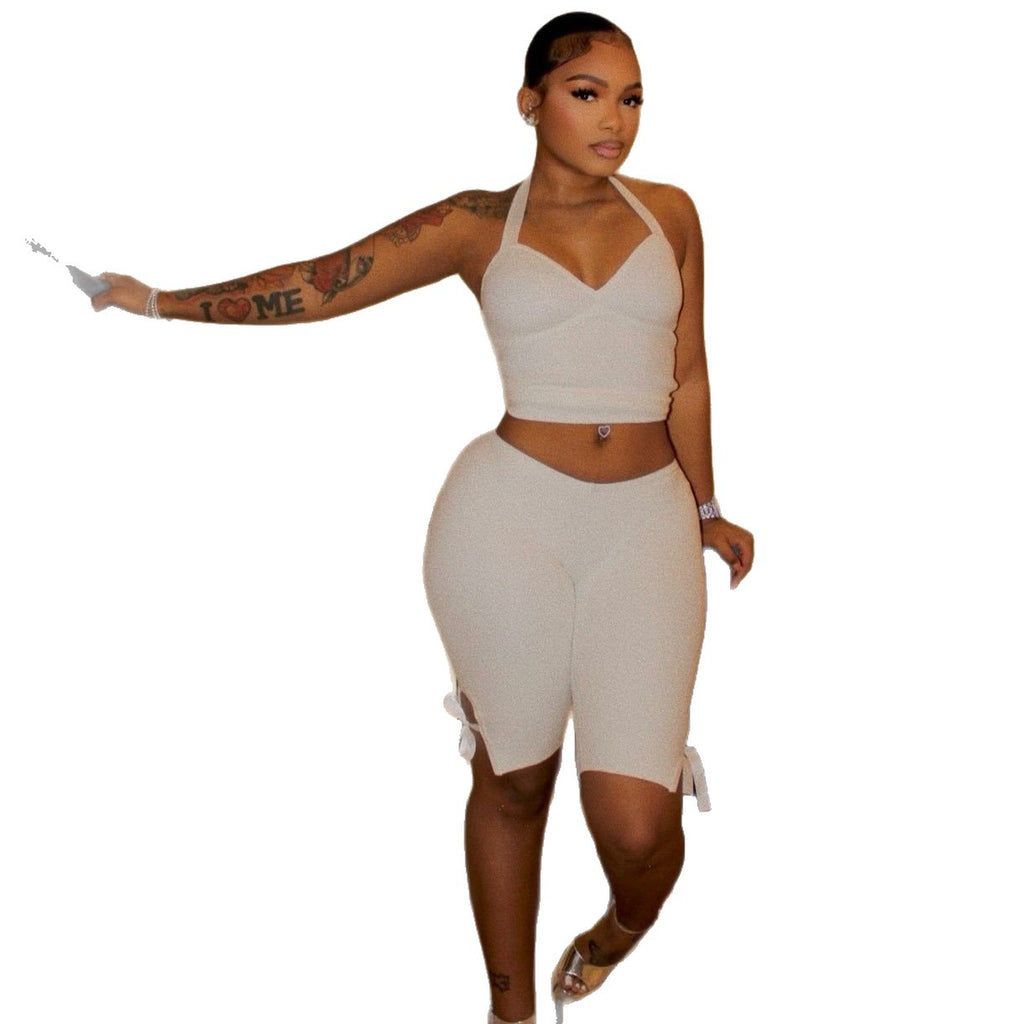Model wearing a white halter crop top and white side-tie cropped pants on a white background.