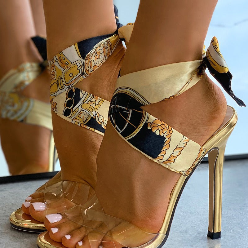 Gold stiletto sandals close-up showing printed scarf ankle ties