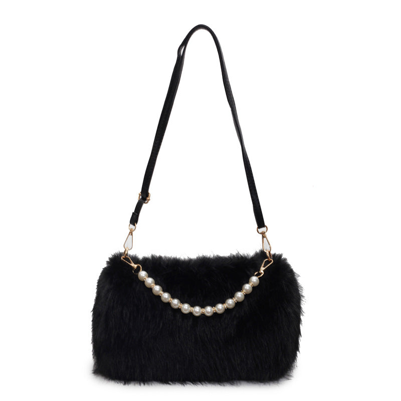 Black plush shoulder bag with pearl-style front row and adjustable single strap on a white background.