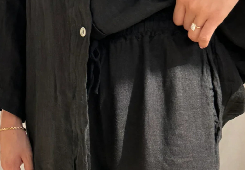Close fabric and elastic-waist detail of the black shirt and trouser set.