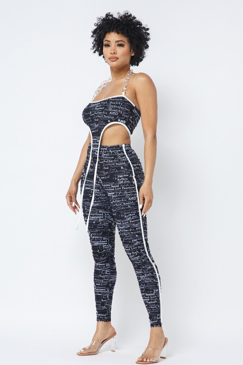 Black-and-white printed crop top and ruched leggings set showing the clear chain halter and white piping, side view