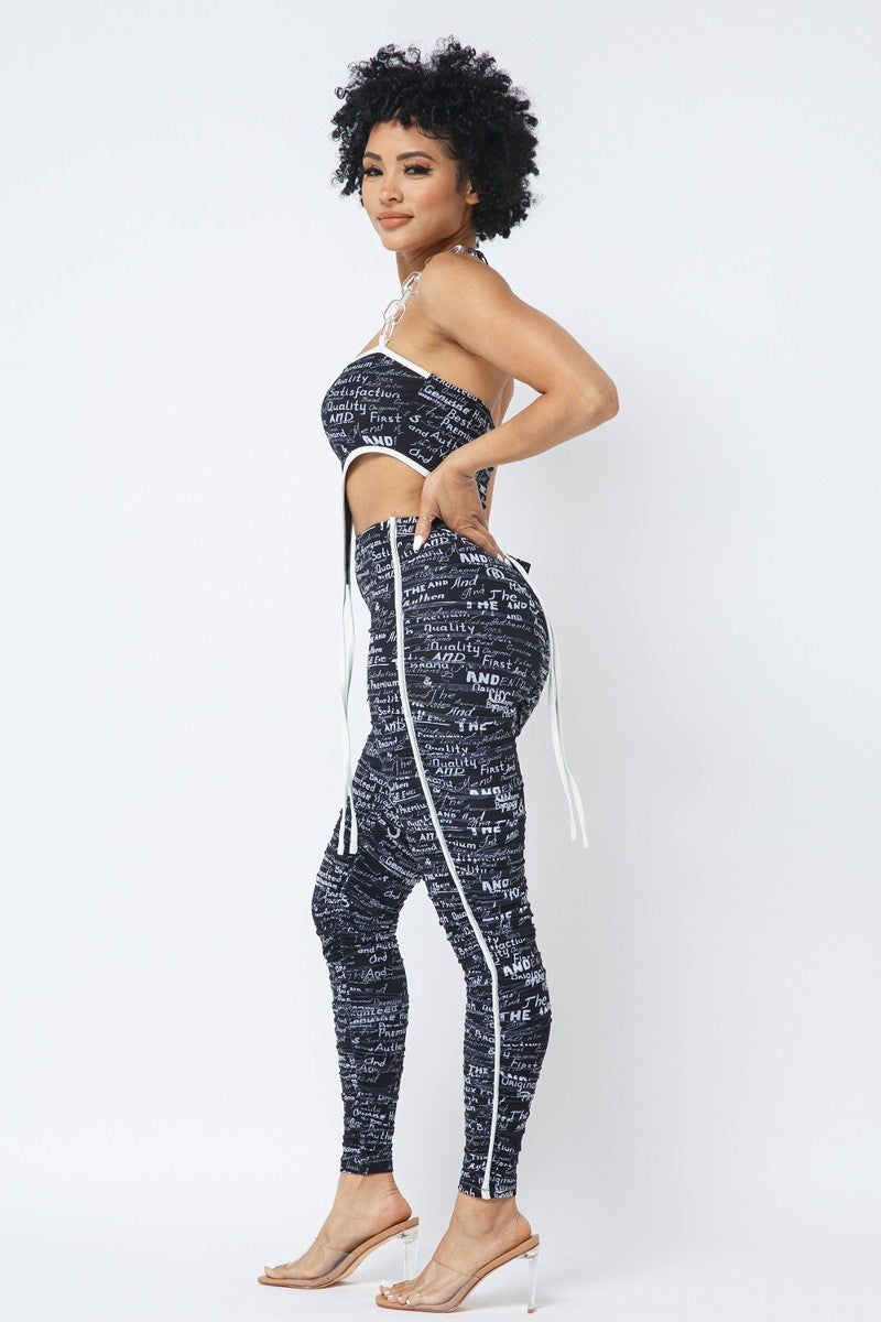 Black-and-white printed chain-halter crop top and matching ruched leggings, rear three-quarter view