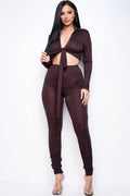Adult model wearing the dark-brown two-piece set with a collared long-sleeve tie-front crop top and high-waist pants with stacked lower-leg ruching
