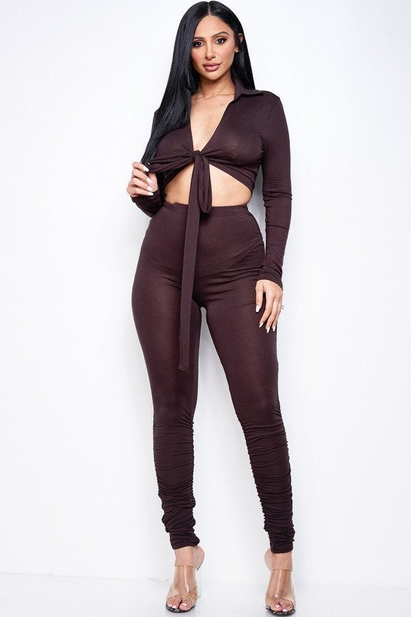 Adult model wearing the dark-brown two-piece set with a collared long-sleeve tie-front crop top and high-waist pants with stacked lower-leg ruching