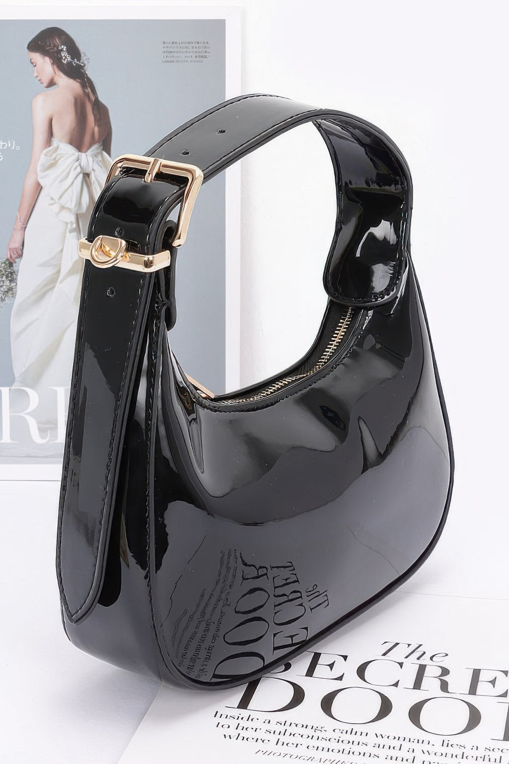 Black Enamel Hobo Bag side view showing gold buckle, D-ring hardware and curved zip-top opening