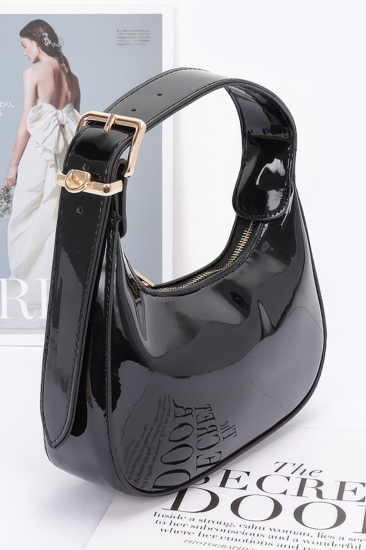 Black Enamel Hobo Bag side view showing gold buckle, D-ring hardware and curved zip-top opening