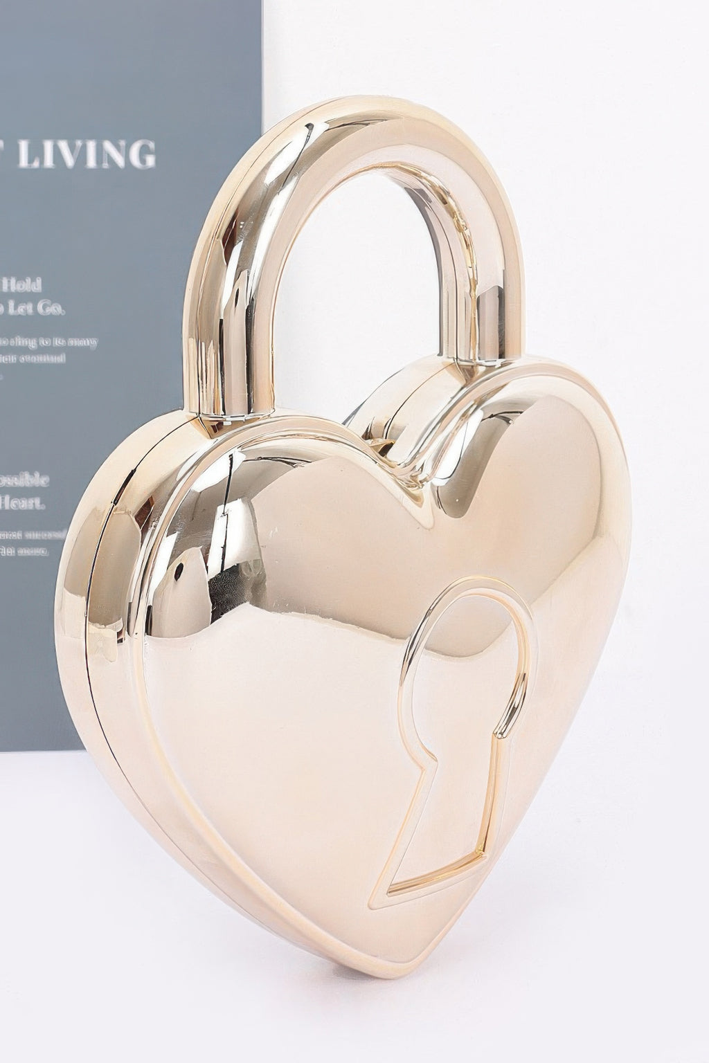 Gold heart-shaped Metallic Acrylic Bag showing mirror finish, integrated handle and raised keyhole motif, angled view