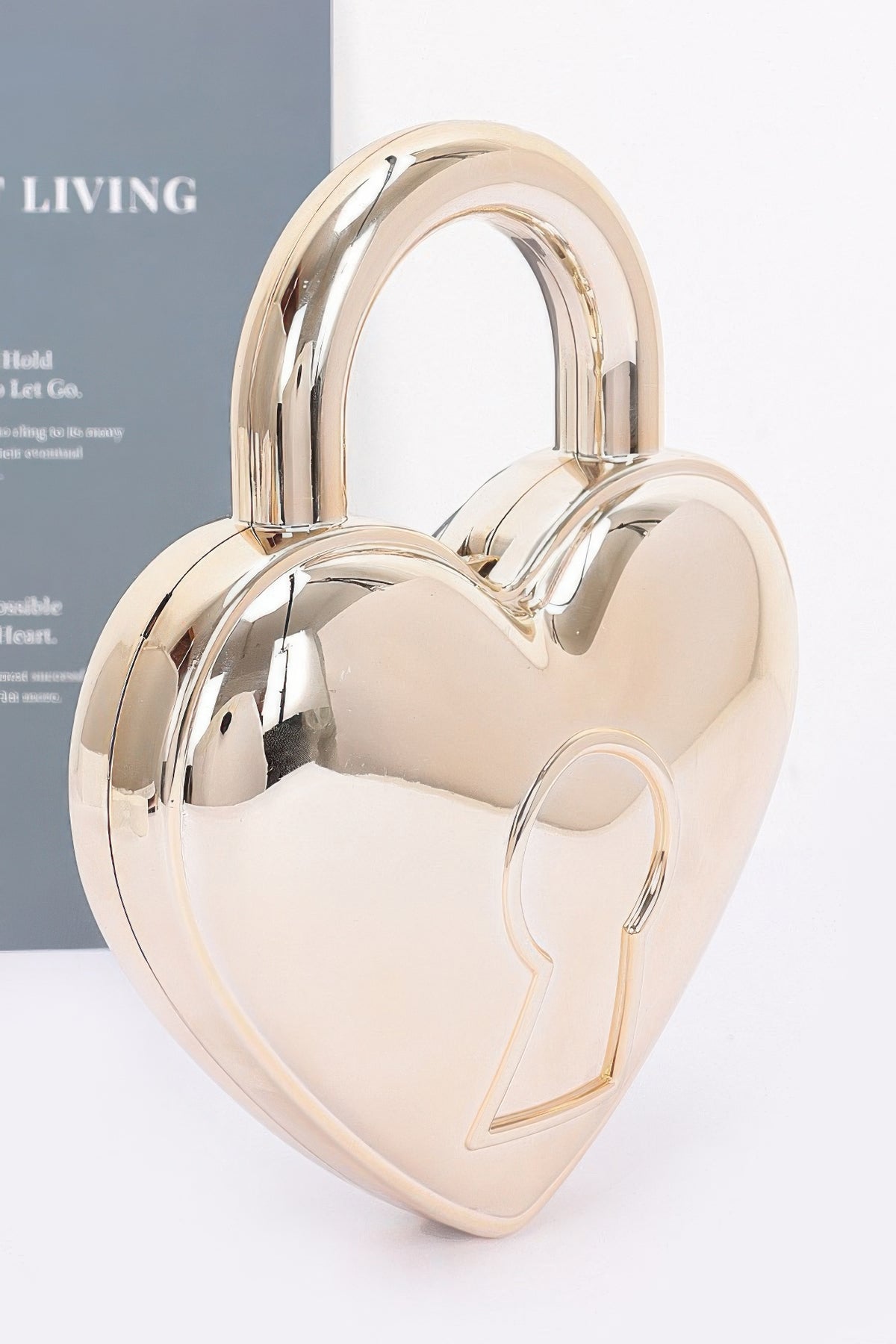 Gold heart-shaped Metallic Acrylic Bag showing mirror finish, integrated handle and raised keyhole motif, angled view