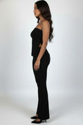 Side view of the black ribbed tube top slit and matching flare pants