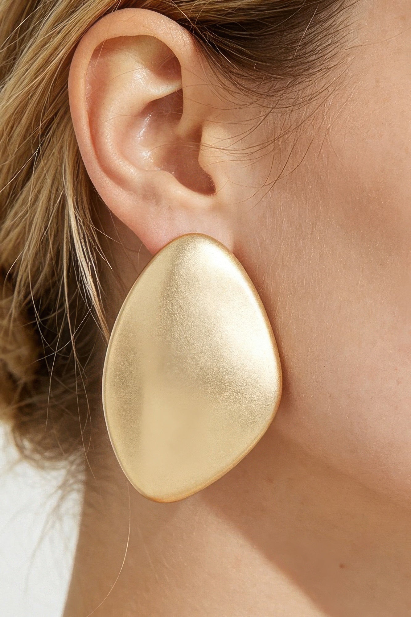 Model wearing the gold-tone Power Plate statement earring