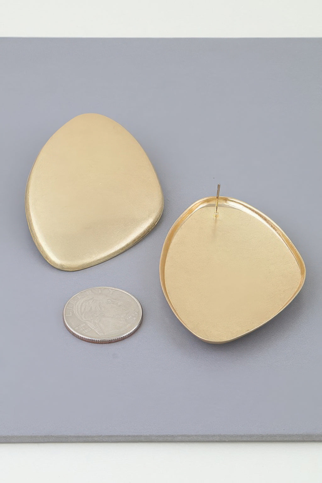 Gold-tone Power Plate earrings shown beside a coin for scale