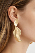 Model wearing the gold-tone Liquid Motion sculptural swirl earring