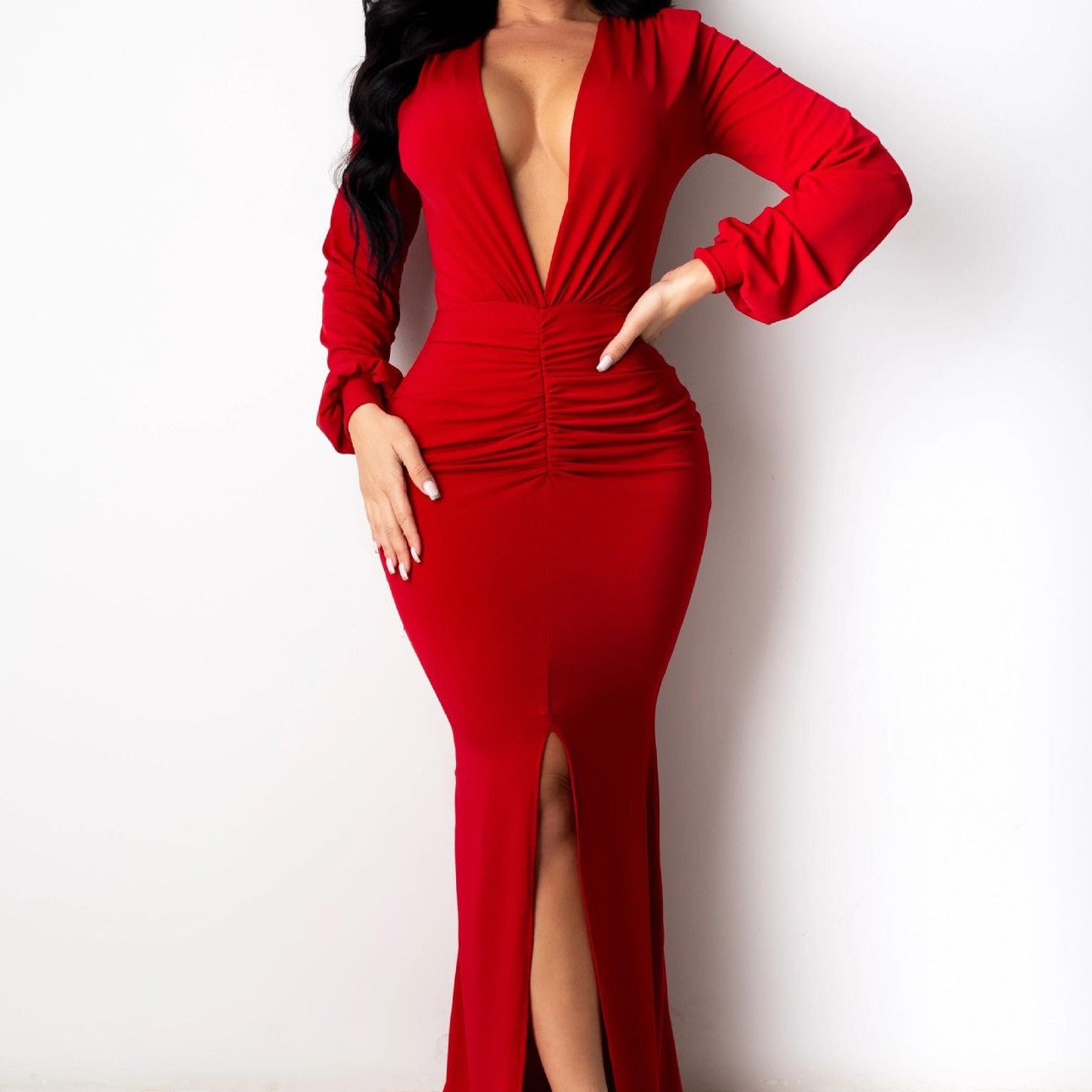 Close front view of an adult model wearing the red Spotlight Status Plunge Maxi Dress, showing the deep V neckline, gathered waist, long sleeves, and front slit.