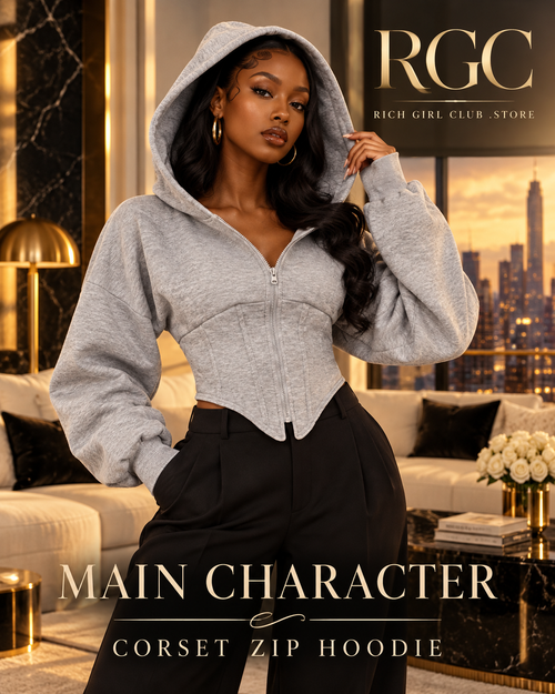 Confident adult model wearing the grey Main Character Corset Zip Hoodie in a luxury penthouse campaign.