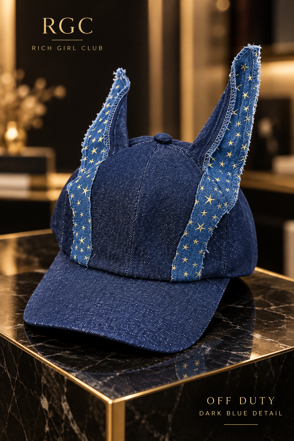Off Duty Dark Blue denim cap by Rich Girl Club shown in detail with a dark indigo crown, blue ear panels with small yellow stars, a curved brim, and raw edges.