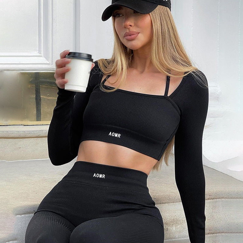 Black rib-knit crop top and pants, seated model holding a cup, close lifestyle view
