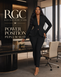 Power Position Peplum Suit in black on an adult model in a penthouse boardroom, showing the deep-V long-sleeve peplum jacket, layered ruffle hem, and slim trousers.